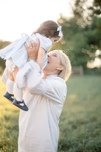 Mother lifting her toddler in the air outdoors