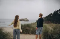 Destination engagement photographer Grace Wan captures a couple standing on a beach on the Oregon coast as they look out into the ocean.