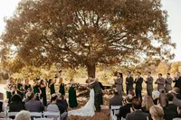 Newlyweds share their first kiss as husband and wife in front of a large tree at Chesapeake Bay Foundation Weddings and Events