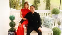 Wedding videography still of couple in red and black formal attire posing with topiary plants