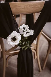 close up of black styled ceremony chair with white floral decor