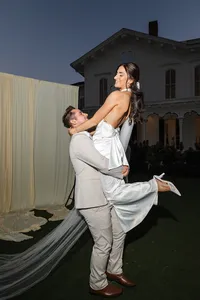Joyful groom lifting bride in silk dress outside venue for Madelyn C testimonial on Dove and Fox website
