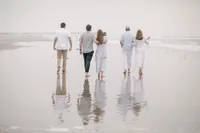 Family walking along the shoreline, photographed from behind