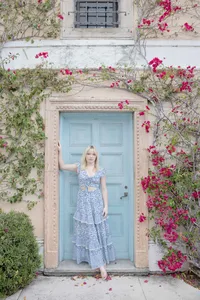 Woman's branding portrait in front of a blue door with flowering vines