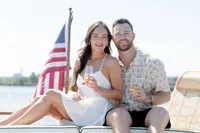 Couple sitting on a waterfront dock with an American flag during their engagement session