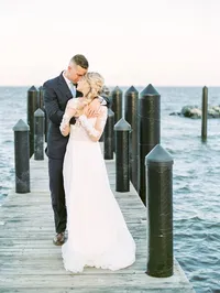 A bride and groom embrace on a 125-foot dock over the Chesapeake Bay