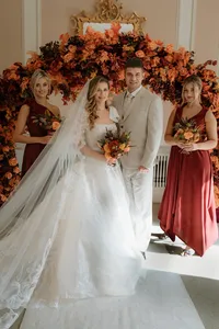 Wedding couple and bridesmaids in front of autumnal wedding styling floral arch