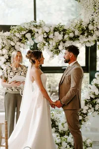 Wedding couple exchanging vows in front of a heart-shaped white rose wedding arch