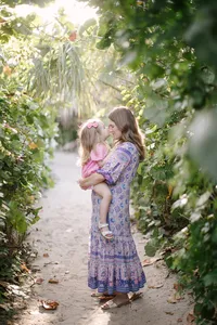 Mother carrying her child along a tropical garden pathway near the beach