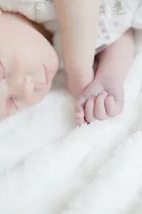 Close-up of a sleeping newborn's face beside their tiny hand