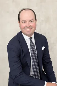 Corporate headshot of a man seated in a navy suit