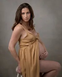 Pregnant woman in a mustard gown during her maternity studio portrait session
