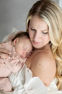 Mother holding her sleeping newborn cheek to cheek during a studio portrait session