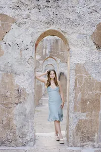 Woman's branding portrait standing in a stone archway corridor