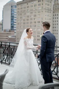 Bride and groom share a laugh together on a city balcony overlooking the Philadelphia skyline