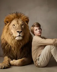 Fine art portrait of a teen seated beside a lion