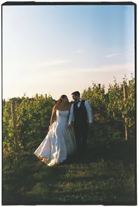 Grand Rapids film wedding photography of a bride and groom holding hands as they walk through an orchard.