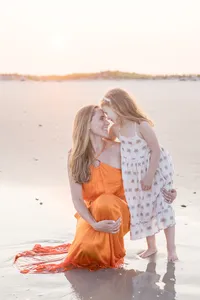 Mother and child embracing at the water's edge in an orange dress