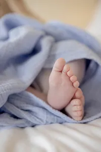 Close-up of newborn baby's feet under a blue blanket