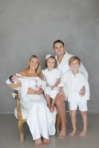 Family of five in matching white outfits with their newborn during a studio portrait session