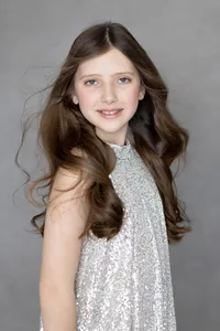 Girl's professional portrait in a sparkly blouse against warm studio tones