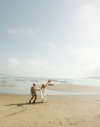 couple in ocean at beach - Photograph of couple standing in ocean water at beach with soft natural light and calm coastal backdrop
