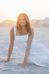 Woman's branding portrait sitting on the beach in a white dress