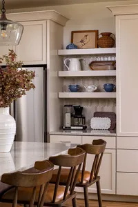 Styled open shelving in an Asheville, NC kitchen with creamy cabinets and a vase full of fall stems.
