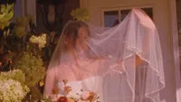 Wedding videography still close-up of bride's pink-tinted veil with floral bouquet