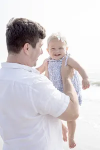 Father holding his toddler daughter during a beach portrait session
