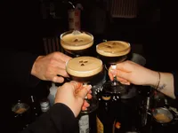 three hands holding espresso martinis and cheersing the drinks