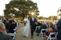A bride and groom with huge smiles on their faces walk arm in arm back down the beach ceremony aisle at Chesapeake Bay Foundation Weddings and Events