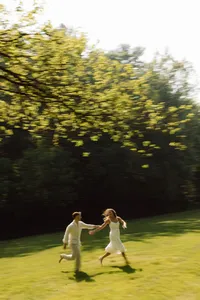 couple dancing on lawn at dusk - Photograph of bride and groom dancing together on open grass lawn during evening light with trees