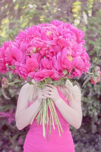 Woman posing with a large bouquet of flowers in front of her face