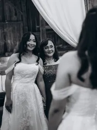 Black and white photo of a bride looking into a mirror as she stands next to her mom on her wedding day.