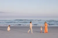 Family walking together along the shoreline during their beach portrait session