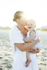 Mother holding her toddler in backlit beach light