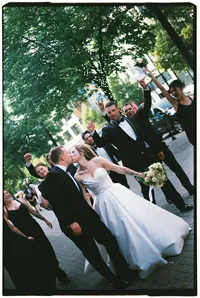 A bride and groom kiss as their bridal party walks behind celebrating, by Grace Wan destination wedding photographer.