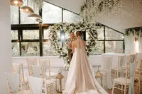 bride in front of a heart-shaped white rose wedding arch