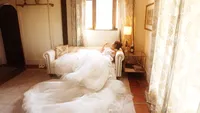 Wedding videography still of flowing white wedding dress displayed in bridal suite with windows and natural light