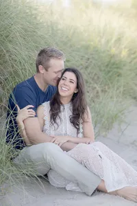 Couple embracing in dune grass during their coastal engagement session