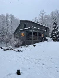 Snow-covered Brookside Retreat surrounded by winter woods