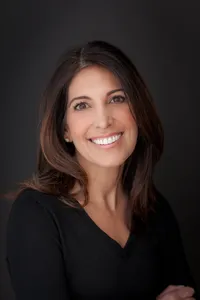 Professional headshot of a woman against a dark background