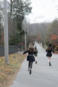 Siblings running down a tree-lined road during their portrait session