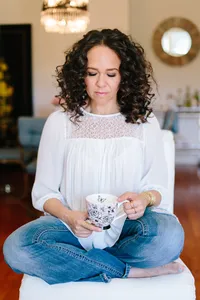 women's hands wearing rings and a bracelet hold a pink toille cup patterned in black and white.