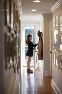 Child standing in a hallway lined with frames