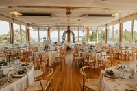 The Canvasback Dining Room at Chesapeake Bay Foundation Weddings and Events set up for a reception with wooden chairs and a floral arch