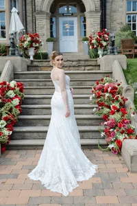bride in front of wedding venue with red and burgundy floral displays styled around the steps