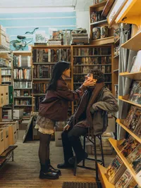 A woman holds her fiancés face during a cozy engagement session in the Grand Rapids Michigan library.
