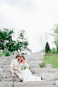 A bride and groom embracing each other while sitting on steps taking their wedding portraits.